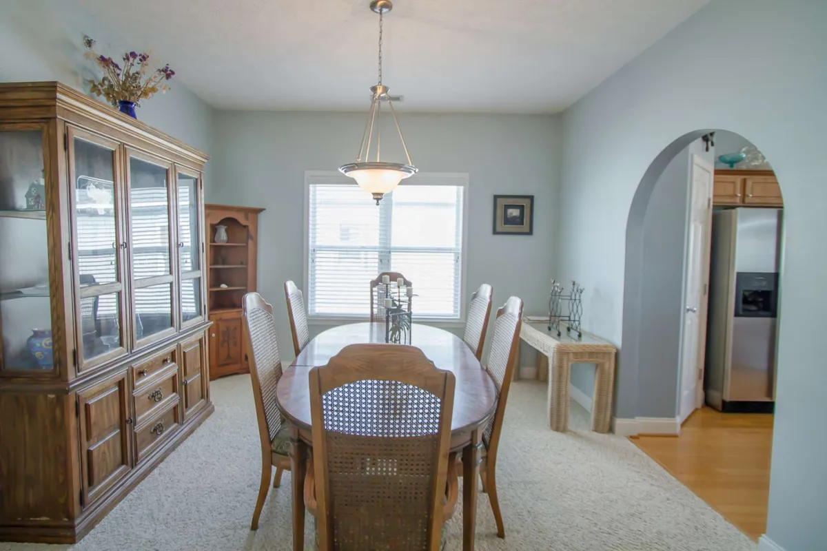 A warm dining area is the focal point, featuring a sturdy dining table and a charming china cabinet. Sunlight streams in through the windows, creating an inviting atmosphere for social gatherings and celebratory meals.