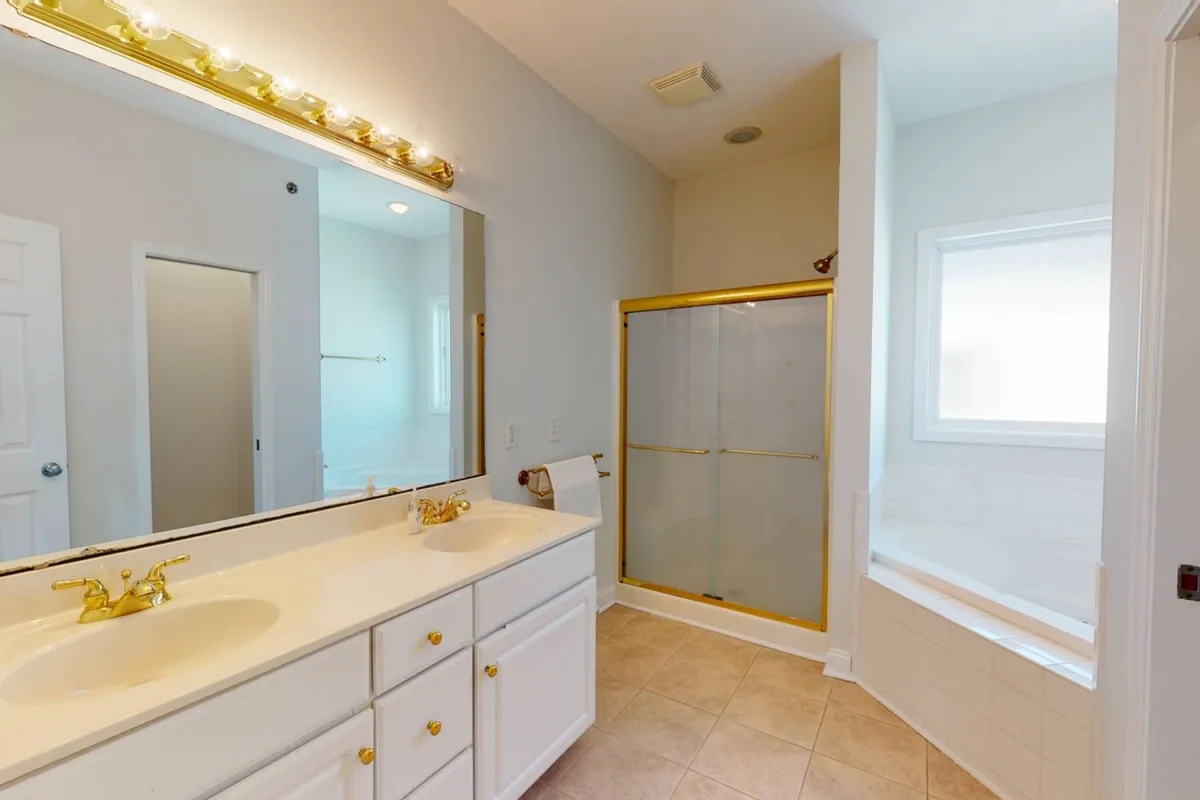 A modern bathroom featuring a large mirror, deep bathtub, and enclosed shower. The room is pristine and thoughtfully prepared, evoking feelings of refreshment and relaxation upon arrival.